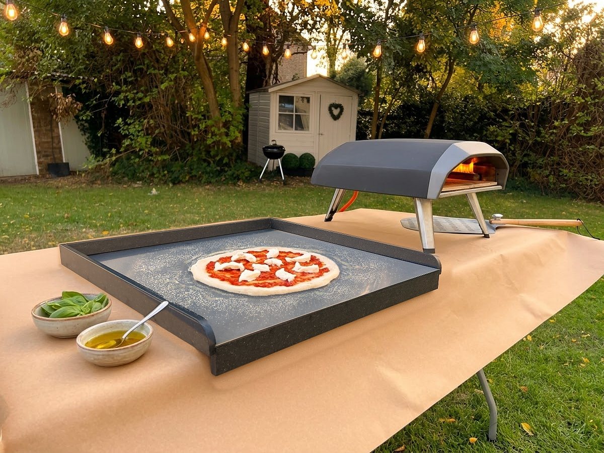Stendì with a pizza ready to go into an outdoor pizza oven at dusk